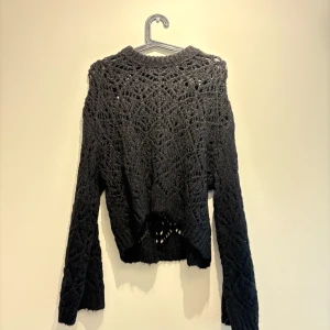 Svart stickad tröja från Zara - Säljer en svart stickad tröja från Zara i storlek S. Tröjan har ett snyggt virkat mönster med genombrutna detaljer och lång ärm. Perfekt för lager-på-lager och ger en cool vibe till din outfit.
