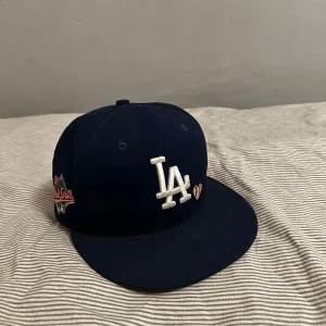 LA Dodgers keps från New Era limited edition - Säljer en limited edition LA Dodgers “Team Heart” keps från New Era (59FIFTY).  1988 World Series patch  Litet hjärta + “Love & Hustle = Game” brodyr Äkta och ovanlig modell, släppt aug 2022 Storlek: 7 3/8 , 58,7 cm Köpt 2022, knappt använd då jag haft den som samlarobjekt Värd runt 700-800 kr  Kan tänka mig sälja för lite mindre  