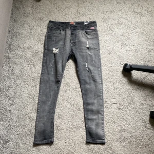 Grå slitna skinny jeans från Levis - Säljer ett par grå jeans från Levis med skinny fit och slitna detaljer på benen. Jeansen har klassisk femficksdesign, Levis-logga på fickan och är i stretchigt jeanstyg. Perfekta för dig som gillar en edgy och modern look.