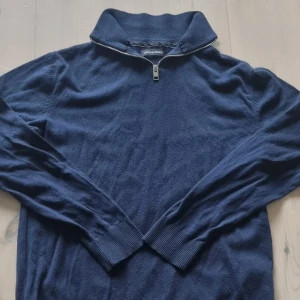 Marinblå half zip tröja Jack & Jones - Mörkblå långärmad tröja från Jack & Jones med hög krage och half zip-dragkedja. Tröjan är ribbad vid ärmslut och nederkant och har en klassisk, stilren look. Perfekt för lager-på-lager och passar till det mesta. Priset är inte hugit i sten!