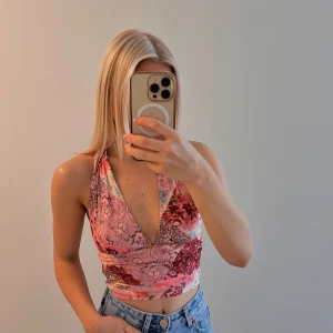 Blommig halterneck croppad topp - Säljer en blommig halterneck topp i rosa och röda toner. Storlek XS