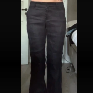 Svarta linnebyxor med bootcut - Snygga svarta linnebyxor med bootcut och låg midja. Byxorna har klassiska fickor fram, bälteshällor och stängs med dragkedja och knapp. Perfekta för en clean och stilren look. Aldrig använda. Nypris 499kr