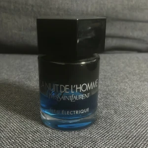 YSL La Nuit De L'Homme Bleu Électrique - En snygg parfymflaska från Yves Saint Laurent, La Nuit De L'Homme Bleu Électrique. Flaskan är rund med svart och blå glas, och har en stor svart sexkantig kork. Parfymen har en elektriskt blå färg som syns genom glaset. Perfekt för dig som gillar exklusiva dofter. 100ml flaska, ungefär 45 ml kvar( tar inte emot returer)