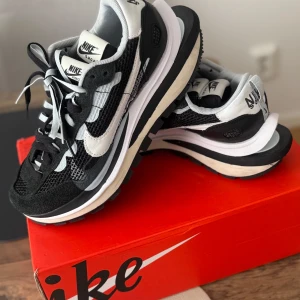 Nike x Sacai svartvita sneakers - Nike x Sacai sneakers i svart och vitt med dubbla snören och cool mesh-paneler. Snygg vågig design på sidan, vit swoosh och chunky sula. Kombination av mocka och mesh ger en modern vibe. Perfekta för dig som vill sticka ut med streetstyle. Jag har två stycken. Size 41 och 36