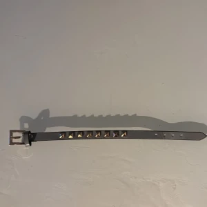 Valentino arband  - Snyggt svart bälte i skinn med fyrkantiga guldfärgade nitar längs mitten. Bältet har klassiskt spänne och flera hål för justering. Perfekt accessoar för att ge outfiten en edgy vibe. (Ej äkta)