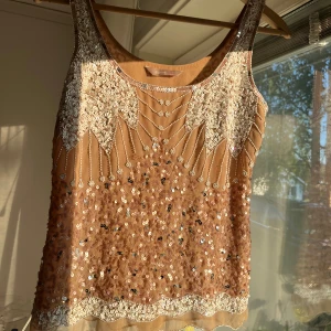 Beige paljettlinne - Sååå fin festtopp med silvriga och vita detaljer, finns tecken på användning men inget man märker 💗Säljer då jag har många liknande!