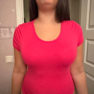 Rosa croppad topp från SHEIN - Säljer en snygg rosa croppad topp från SHEIN med korta ärmar och rund halsringning. Toppen har en öppen detalj i ryggen och är figurnära i modellen. Perfekt för dig som gillar färg och vill sticka ut lite extra.