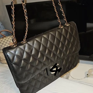 Svart stilren design väska  - En svart stilren och elegant design väska med ett monogram och silver detaljer. Använd några gånger med den är lite för stor för mig tyvärr, den förtjänar bli älskad. Kolla gärna in min profil. 