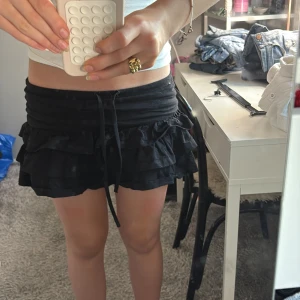 Supergullig svart kjol med volanger!💞 - Supersöt svart kortkjol med flera lager volanger och hängare snören man kan knyta till en rosett! 🩷🩷