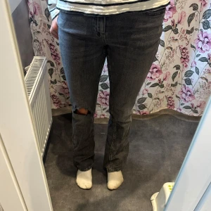 Grå bootcut jeans med hål på knät - Säljer ett par grå jeans med bootcut-modell och snyggt hål på ena knät! Jeansen är typ svarta med lite grå nyans!🩶