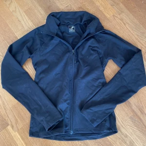 Svart träningsjacka - Svart träningsjacka från Energetics i sportig modell med hel dragkedja framtill och hög krage. Jackan är tight, lätt och smidig, perfekt för träning. Passformen är tight men stretchig vilket gör den väldigt bekväm. Enkel och stilren design som funkar till det mesta. Den är knappt använd 💞