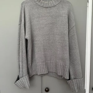 Grå stickad tröja från NA-KD - Mysig grå stickad tröja från NA-KD med bred ribbad kant vid hals, ärmslut och nederkant. Tröjan har en loose fit och långa ärmar, perfekt för lager-på-lager under kyliga dagar. Enkel och stilren design som funkar till allt. Använd typ 2-3 gånger❤️❤️❤️