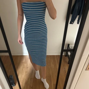 Blåvit randig tubklänning med slits - Säljer en blå och vit randig tubklänning i ribbad bomull. Klänningen är lång, figurnära och har en snygg slits på sidan. Passar både xs och s då den är väldigt stretchig. 