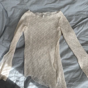 Vit spetsblus - Supersöt vit långärmad blus från House i storlek XS. Blusen är helt i spets med blommigt mönster och har en asymmetrisk passform