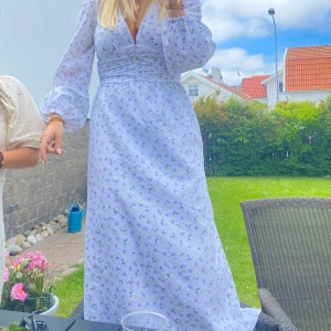  blommig långklänning med puffärm - Intressekoll på långklänning. Perfekt för sommarens alla tillfällen, köpt förra året men endast anmänd ett par gånger. Likt adoore klänningen. Storlek 36