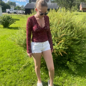 Vinröd spetsblus med v-ringning - Säljer en vinröd långärmad blus i spets med djup v-ringning och figurnära passform. Blusen har genombrutet spetsmönster och långa ärmar, perfekt för dig som vill ha en snygg och feminin topp till sommaren.