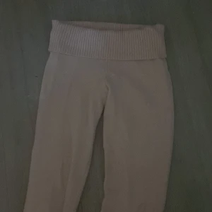 Stickade ljusrosa byxor Gina Tricot - Mysiga stickade byxor från Gina Tricot i en ljusrosa färg. Byxorna har en bred ribbad midja som är superbekväm och boot cut bem. Perfekta för chill dagar hemma eller när du vill vara extra comfy.