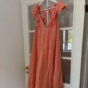 Långklänning - Så fin långklänning i korall. Den har fina volanger och knytning i ryggen. Aldrig använd, endast testad. 