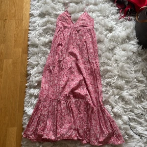 Rosa blommig långklänning med smala axelband - Supersöt långklänning i rosa med småblommigt mönster och smala axelband. Klänningen har v-ringning och volang nertill, perfekt för varma dagar. Lätt och luftig modell i storlek S från Zara 