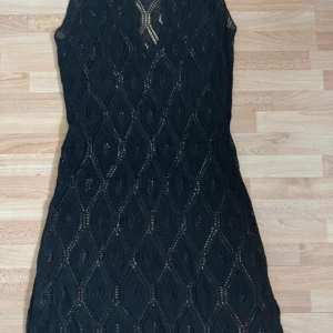 Svart stickad kortklänning H&M - Svart ärmlös stickad kortklänning från H&M med snyggt hålmönster i diamantform och v-ringad hals. Perfekt för dig som gillar en trendig och bekväm look. Klänningen har en figurnära passform och är superenkel att styla. Hade på mig en gång. Längd 104cm. Storleklapp avklippt, men är str.38