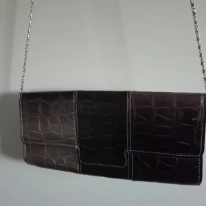 Svart och grå kuvertväska med kedja - Kuvertväska i svart och grått med croco-mönstrad yta och silvrig kedjerem. Väskan har rektangulär form, tydliga kontrastsömmar och stilren look. Perfekt för dig som gillar en edgy men klassisk vibe.