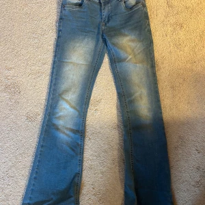 Blå bootcut jeans från D-XEL - Snygga blå jeans från D-XEL i bootcut-modell med klassisk femficksdesign. Jeansen har ljusa slitningar framtill och bak, normal passform och är tillverkade i mjukt denimtyg. Perfekta för dig som gillar en retroinspirerad look.