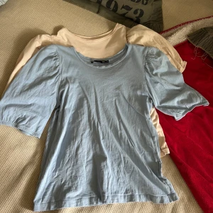 Två puffärm t-shirts från 157 XS - Säljer två t-shirts från 157 i storlek XS. Ena är ljusblå och den andra beige, båda med puffade korta ärmar och rund hals. Materialet är mjuk bomull, perfekt för chill dagar. Snygg enkel stil med lite volym på axlarna. Båda för 20kr