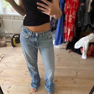 Lågmidjade ljusblå  - Säljer ett par klassiska jeans i ljusblå tvätt med låg midja och rak passform. Jeansen har fem fickor, knappgylf och slitna detaljer vid bensluten för en cool vintagekänsla. Perfekta för dig som gillar avslappnad och tidlös stil.