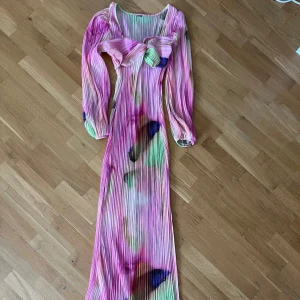 Färgglad långklänning - Säljer en unik långklänning med plisserat tyg i flera färger som rosa, grön, blå och lila.