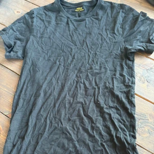 Svart t-shirt från Polo Ralph Lauren - Svart t-shirt från Polo Ralph Lauren med klassisk passform och korta ärmar. T-shirten har en broderad logga i vitt på bröstet och är tillverkad i mjuk bomull. Perfekt basic-plagg med stilren look.