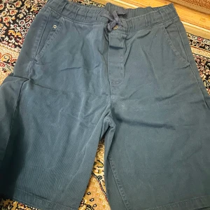 Blå joggershorts från H&M med snörning - Snygga blå joggershorts från H&M i storlek 158/164. De har elastisk midja med snörning, två sidofickor och är gjorda i mjuk bomull. Perfekta för chill dagar och har en enkel, loose passform som är skön att bära.