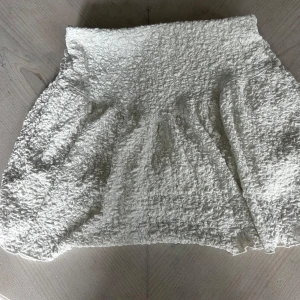 Vit kortkjol från Gina Tricot - Supersöt vit kortkjol från Gina Tricot med coolt ribbad och texturerad yta. Kjolen har en lätt volang och är tillverkad i ett mjukt syntetmaterial som känns skönt mot huden. Perfekt för dig som gillar en fräsch och trendig look.💗 jag har aldrig använt den och jag bor i Danderyd 💗 priset går att diskutera