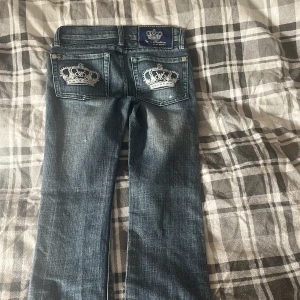 Victoria beckham jeans - Snygga blå jeansbyxor från Von Dutch med slitningar och coola broderade kronor på bakfickorna. Klassisk femficksmodell med silverfärgade nitar och knappar. Jeansen har en rak passform och är tillverkade i jeansmaterial.