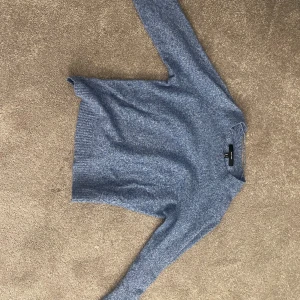 Blå stickad tröja från vero Moda  - Mysig blå stickad tröja från vero Moda med rund hals och ribbade muddar vid ärmslut och nederkant. Perfekt för kyliga dagar och enkel att matcha med jeans eller kjol. Tröjan har en klassisk passform och är långärmad.