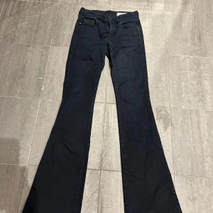 Svarta low waist bootcut jeans Diesel Sandy-B - Svarta jeans från Diesel, modell Sandy-B, med regular slim-passform och bootcut-ben. Jeansen har klassisk femficksdesign, bälteshällor och normal midja. Snygg mörk tvätt och stretchigt bomullsmaterial för en bekväm känsla.