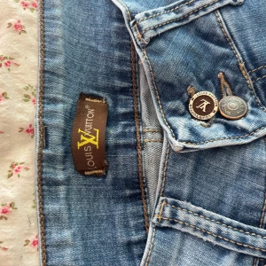 Blå jeans  - Snygga blå jeans med klassisk femficksdesign och detaljerade knappar. Jeansen har ljus tvätt och kontrastsömmar, vilket ger en fräsch och trendig look. Köpta på vintagebutik i Paris för 1799kr