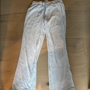 Ljusgrå mjukisbyxor med snörning - Säljer ett par ljusgrå mjukisbyxor med snörning i midjan. Byxorna har raka ben och är tillverkade i ett mjukt och bekvämt material, perfekta för chill dagar hemma eller när du vill vara extra comfy.