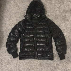 Glansig peak performance jacka - Super fin glansig pufferjacka från peak performance i strl xs 🙌🏻perfekt till vintern super skön varm och gosig !! Har ett litet skav som jag satt över en lapp på som syns på 6e bilden,men som knappt syns när man använder jackan 😇annars är den i väldigt fint skick utöver de 😚passar både dam och herr !!är svart i dagsljus osv men med blixt blir den svart/blå