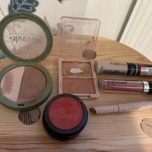 Sminkpaket med bronzer, concealer & gloss - Ett sminkpaket med bronzer och puder i ett pack, ett grönt p pack med brun  highlighter och ljusbrun rouge, L'Oréal Infaillible 24H concealer, SHEGLAM  läspenna och läppstift ljusbrun, krämrouge i röd ton samt Boss Gloss läppglans i rosa nyans. Priset är 250 kr. 