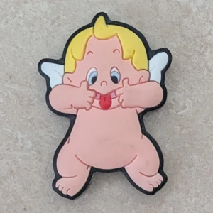 Roliga ängel magnet  - Säljer magnet i form av en tecknad ängel med blont hår, vita vingar och rosa hud. Ängeln gör en busig min och sticker ut tungan. Färgerna är ljusa och designen är lekfull, perfekt för dig som gillar unika och skojiga magneter.