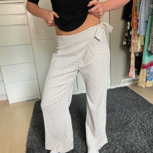 Prickiga omlottbyxor från Zara - Snygga vita omlottbyxor från Zara med svarta prickar och knyt i midjan. Byxorna har en loose och wide passform med hög midja och är tillverkade i ett mjukt, lätt material. Perfekta för en chill och trendig look.
