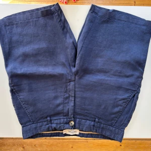 Marinblå linneshorts Dressmann XS. Sparsmakat använda! - Snygga marinblå shorts från Dressmann i ren linne. Modellen har midwaist, knappstängning och praktiska fickor med knappdetaljer. Sparsmakat använda! Storlek XS
