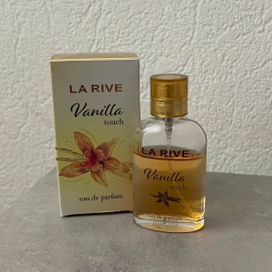 La Rive Vanilla Touch parfym - La Rive Vanilla Touch eau de parfum med söt och varm vaniljdoft. Flaskan är genomskinlig med guldig kork och text, och kommer i en ljus ask med vaniljblomma på framsidan. Perfekt för dig som älskar mjuka, krämiga dofter med en hint av sötma.