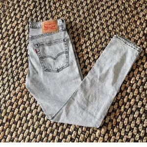 LjusGråa Levis  jeans - Säljer ett par klassiska gråa Levis jeans med slim fit passform och femficksmodell. Jeansen har knappgylf och den ikoniska Levis-lappen bak i midjan. Perfekta för dig som gillar vintagekänsla och tidlös stil.nypris 800kr.hör av dig vid funderingar🤩
