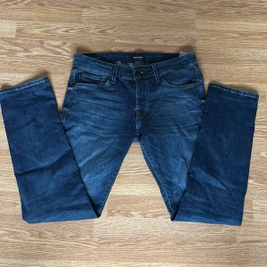 Blå jeans från Jack & Jones - Säljer ett par klassiska blå jeans från Jack & Jones med normal passform. Jeansen har fem fickor, dragkedja och knapp i midjan. Perfekta för dig som gillar en tidlös stil. Nypris 699kr