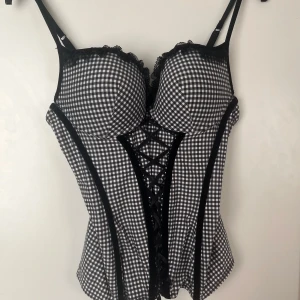Svartvit rutig korsett med snörning - Säljer en svartvit rutig korsett med vadderade kupor och snygg snörning framtill🩷Toppen har justerbara axelband. Perfekt till fest eller till vardag💕Tyvärr förstor för mig. Strl 85A Passar nog även B-kupa 