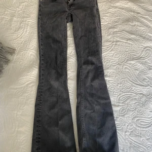 Grå bootcut jeans - Säljer ett par gråa bootcut jeans med klassisk femficksdesign och dragkedja. Jeansen har utsvängda ben och normal passform, perfekta för en avslappnad och trendig look.