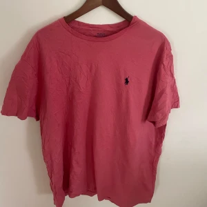 Rosa t-shirt från Polo Ralph Lauren - Säljer en klassisk rosa t-shirt från Polo Ralph Lauren med broderad logga på bröstet. T-shirten har normal passform och är tillverkad i mjuk bomull. Perfekt för en avslappnad stil. Skick 8-9/10