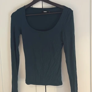 Mörkgrön långärmad topp från BikBok - Säljer en mörkgrön långärmad topp från BikBok med rund, djup ringning. Toppen har en tight passform och är tillverkad i ett mjukt, stretchigt material. Perfekt att styla med jeans eller kjol. Hör av dig till mig vid intresse💕