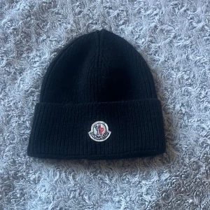 Svart ribbad mössa från Moncler -  Säljer nu min Moncler mössa då jag inte använder den. Storlek funkar till alla.mössan är i ett Väldigt bra skick och 100 % äkta.